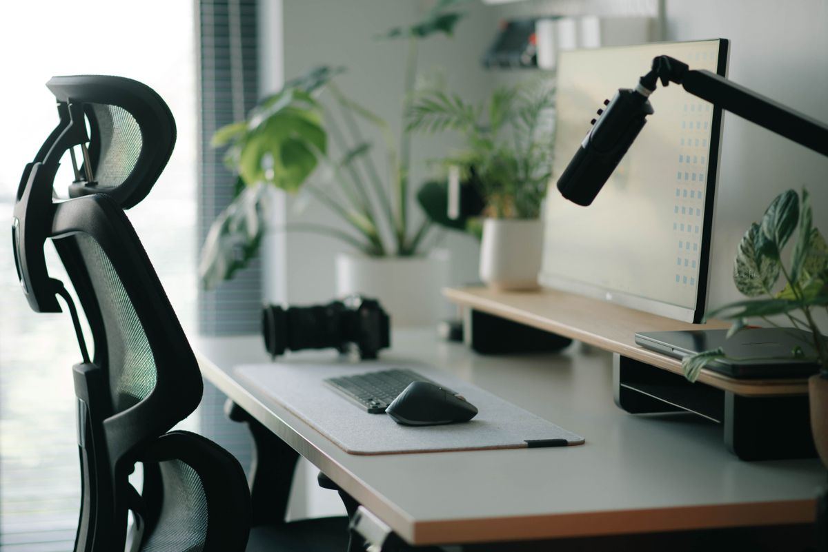 Silla de oficina con respaldo de malla y cabecera frente a un escritorio con monitor
