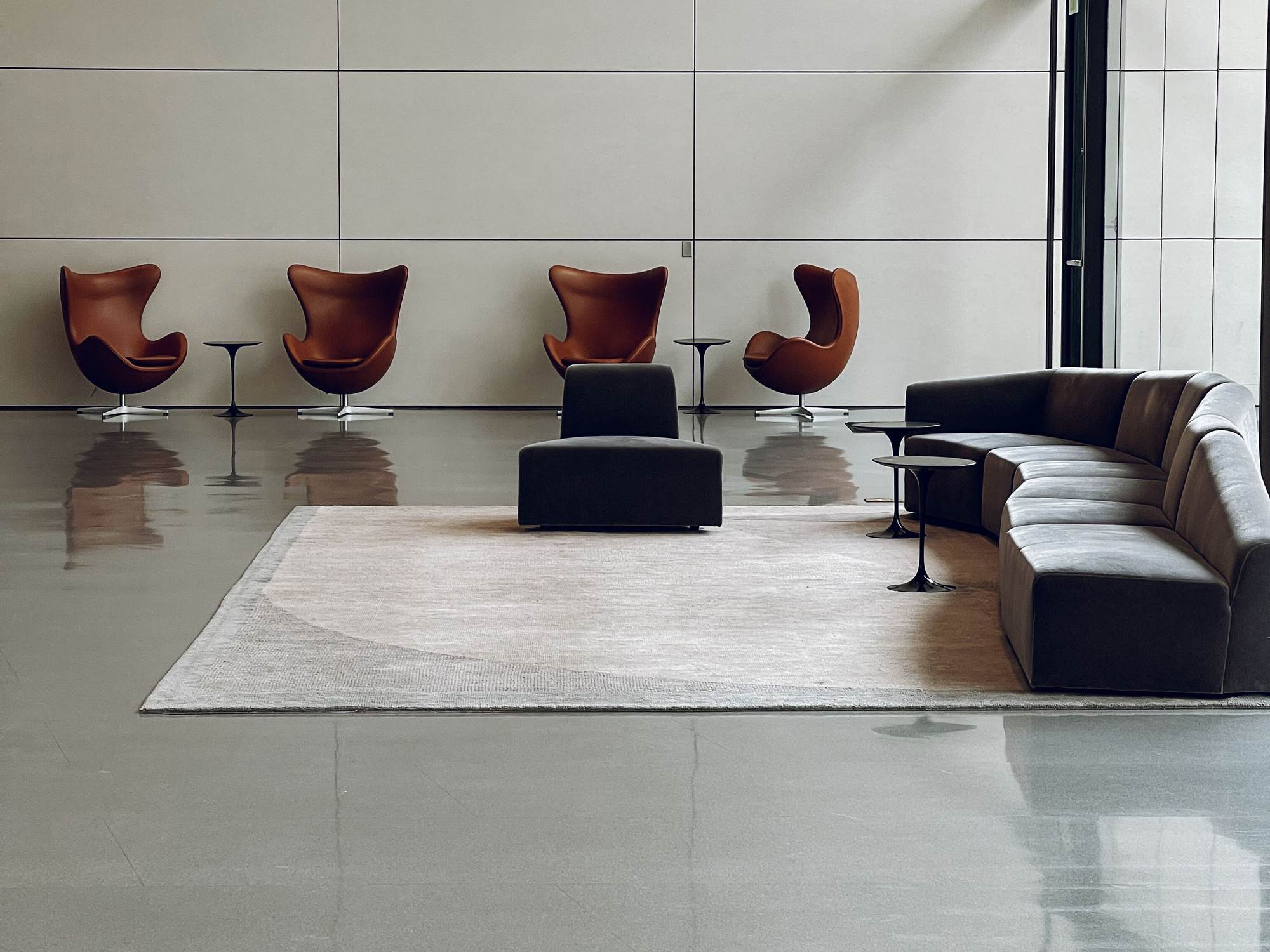 Lobby corporativo amueblado con sillones de piel, sofá modular y mesas de diseño